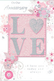 This anniversary card offers a tender tribute to enduring romance, its gentle blend of pastel pinks, silvery greys, and pearl whites evoking the soft light that often settles over Spitalfields' old streets in the early evening. At its centre, the word LOVE stretches across the card, each letter raised and dusted with soft glitter. The letter O is beautifully replaced by a shimmering silver heart, slightly domed and textured, which becomes the luminous focal point of the entire piece. This heart catches and reflects light in a refined sparkle, suggesting both celebration and intimacy. Encircling the central word, delicate blooms open in shades of blush and mauve, their petals softly shaded as if painted in watercolour. Fine flowing lines form stems and swirling tendrils that loop across the card, recalling the loose, natural curves of a florist's hand-tied arrangement prepared for an anniversary surprise near Spitalfields Market or the lanes off Brick Lane. Tiny flourishes-petals in mid-fall, graceful curls, and faint butterflies-add an almost whispering motion, as though a breeze has just passed through a garden. The background remains a reassuring soft pink, allowing the silvery and white details to stand out with clarity. Elegant phrases, including On Our Anniversary and I love you today and always, appear in a slender, flowing script, complementing rather than competing with the artwork. The overall effect is tender, poised, and deeply personal, as if this card were meant to be kept in a special box with ticket stubs, old photos, and the memory of many shared evenings in Spitalfields.